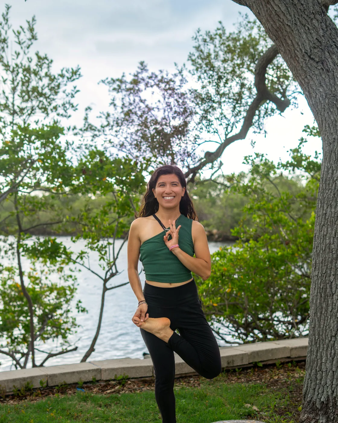 Eva Flowers in tree pose beside the water in Tampa, Florida